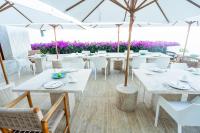um restaurante com mesas brancas, cadeiras e guarda-sóis em Encanto Acapulco em Acapulco