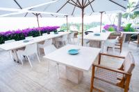 um restaurante com mesas brancas, cadeiras e guarda-sóis em Encanto Acapulco em Acapulco