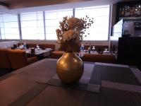 Un jarrón con flores sobre una mesa en un restaurante. en Hotel Tirupati Plaza, en Kota