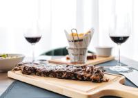 Un trozo de comida en una tabla de cortar con dos copas de vino. en Oporto Fly Hotel, en Maia