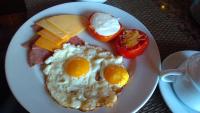 a plate of breakfast food with eggs bacon cheese and tomatoes at Giza City Hotel-الجيزة سيتى اوتيل in Cairo