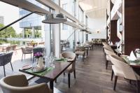 een restaurant met tafels, stoelen en ramen bij Metropol Palace, Belgrade in Belgrado