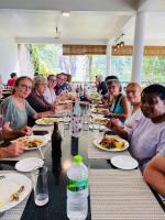 Un grupo de personas sentadas en una mesa comiendo comida en Ramboda Falls PLC, en Ramboda