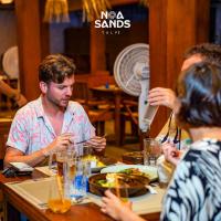 タールにあるNoa Sands By Ceylon Vistasのテーブルに座って食事を楽しむ人々のグループ