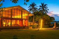 a house with large glass windows and palm trees at Tolani Resort Koh Samui in Lamai
