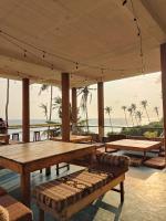 un pabellón con mesas y bancos y el océano en The Sun Set, en Weligama