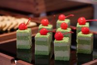 郑州Hampton by HiltonZhengzhou Xinzheng International Airport的一组上面放着樱桃的绿色蛋糕