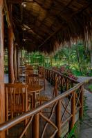 um restaurante com mesas e cadeiras e um telhado de palha em Banana Palms Hotel em Rio Dulce