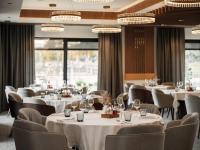 a restaurant with white tables and chairs and windows at Hotel Dunav in Ilok