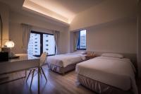 a hotel room with two beds and a desk and window at Hotel Initial-Taichung in Taichung