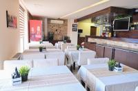 un restaurante con mesas blancas y sillas blancas en Хотел Елица, en Bansko
