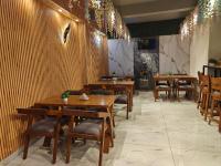 a restaurant with wooden tables and chairs and lights at Tathastu Stay in Dehradun