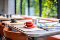 a red coffee cup on a table in a restaurant at TMG Hotel Tebet, Marclan Collection in Jakarta