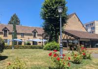 Un poste de luz en el patio de un edificio con flores. en Brit Hotel Confort Alençon, en Alençon