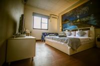a bedroom with a large bed with a painting on the wall at Sabai B&amp;B 澎湖船家寶民宿 in Huxi