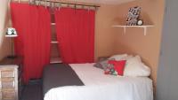 a bedroom with red curtains and a bed with white sheets at Gîte Orus in Orus