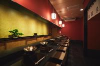 a row of tables in a restaurant with red walls at ご当地ラーメン食べ放題 "The RAMEN HOTEL" -京都嵐山- in Kyoto