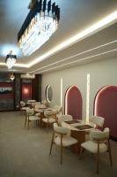 a waiting room with tables and chairs and a chandelier at Hotel Rosevelt in Islamabad