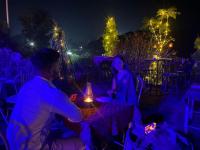 Khalsa Lake View Resort في Jāmb: مجموعة من الناس يجلسون على طاولة في الليل