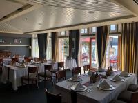 a dining room with white tables and chairs and windows at Poets Cove Resort & Spa in Bedwell Harbour