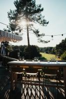 Una mesa con copas de vino en una terraza con un árbol. en Boutique Hôtel La Baignoire, en Lacanau-Océan