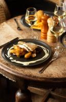 マンダールにあるKjøbmandsgaarden Hotelのテーブルの上に置かれたワイングラスの置かれた料理の皿