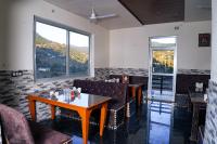 ein Restaurant mit einem Tisch, Stühlen und Fenstern in der Unterkunft Sukoon Inn Hotel & Restaurant in Someshwar