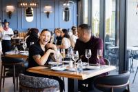 um grupo de pessoas sentadas à mesa de um restaurante em Luxury 2BR Sky Suite City Views & Prime Location na Cidade do Cabo