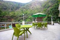 Un patio con mesas y sillas y una sombrilla verde. en Kempty Lake Waterfall Resort - Run by Anaysha Group, en Mussoorie