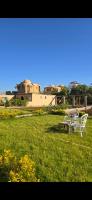 a bench and a table in a field with a building at Leyla Eco Resort Queen Suites in Luxor