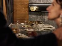 Una mujer sentada en una mesa en un restaurante con una mesa puesta para la cena. en Swissôtel Resort Kolasin, en Kolašin