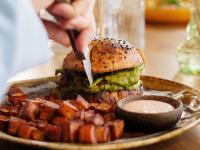 uma pessoa cortando um sanduíche com uma faca em Square Lodge Hotel Accor - La Roche-sur-Yon em La Roche-sur-Yon