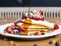 uma pilha de panquecas com fruta num prato em Ibis Darwin Airport Hotel em Darwin