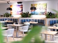 um restaurante com mesas e cadeiras e pinturas na parede em Ibis Darwin Airport Hotel em Darwin