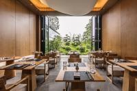 a restaurant with wooden tables and chairs and a large window at 成都释玥森林酒店 in Chengdu