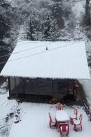 Oreos cafe and stay shangarh في Shangarh: منزل مغطى بالثلوج به كراسي وطاولات حمراء