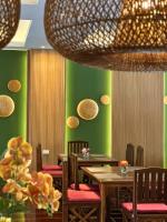 een restaurant met groene muren en houten tafels en stoelen bij Mina Resort and Spa in Loei