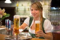 a woman sitting at a bar with two glasses of beer at Gasthof Siegfried Gruber in Hartmannsdorf
