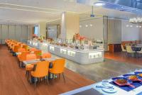 a restaurant with orange chairs and a buffet at Novotel Jinan Airport in Jinan