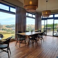 Un comedor con mesa y sillas y grandes ventanales. en Brahman Hills - Gardens, Spa, Hotel & Villas - 5star, en Nottingham Road