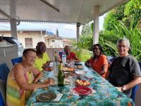 un grupo de personas sentadas alrededor de una mesa con comida en Chez Marino & Charlie, en Le Lamentin