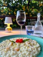 een bord risotto met een rode bloem erop en een wijnglas bij Hotel La Pergola in Amalfi