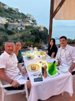 een groep mensen die aan een tafel zitten met eten bij Hotel La Pergola in Amalfi