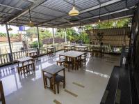 um restaurante com mesas e cadeiras de madeira e janelas em Hotel 7Seas by Solara Hospitality em Vagator