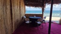 Al QārinOcean Camp的海滩餐厅里的一张桌子和几把椅子