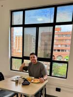 a man sitting at a table in front of a window at Hotel Plaza Mayor 44 in Medellín