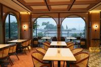 ein Restaurant mit Tischen und Stühlen und großen Fenstern in der Unterkunft Cordela Suites Cianjur in Cianjur