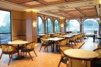 ein Restaurant mit Tischen, Stühlen und Fenstern in der Unterkunft Cordela Suites Cianjur in Cianjur