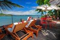 una terrazza con sedie, tavolo e ombrellone di Beach Villa l'Heure Bleue a Madirokely