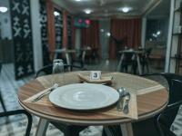 een houten tafel met een bord, vork en mes bij Italian Boy Hotel in Accra